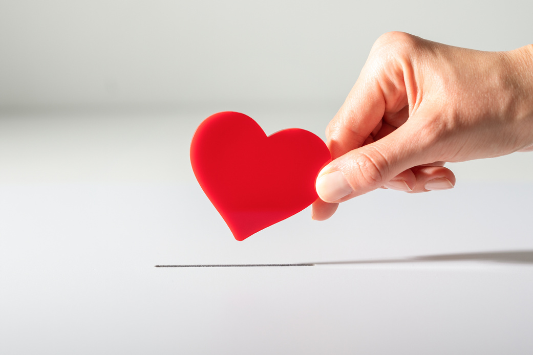 Woman’s Hand Placing Heart in the Donation Slot
